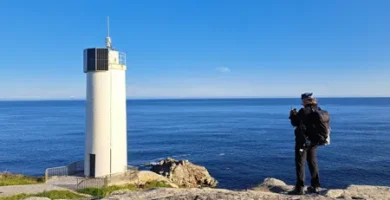 Senderista fotografiando el faro de laxe al amanecer en un dia soleado